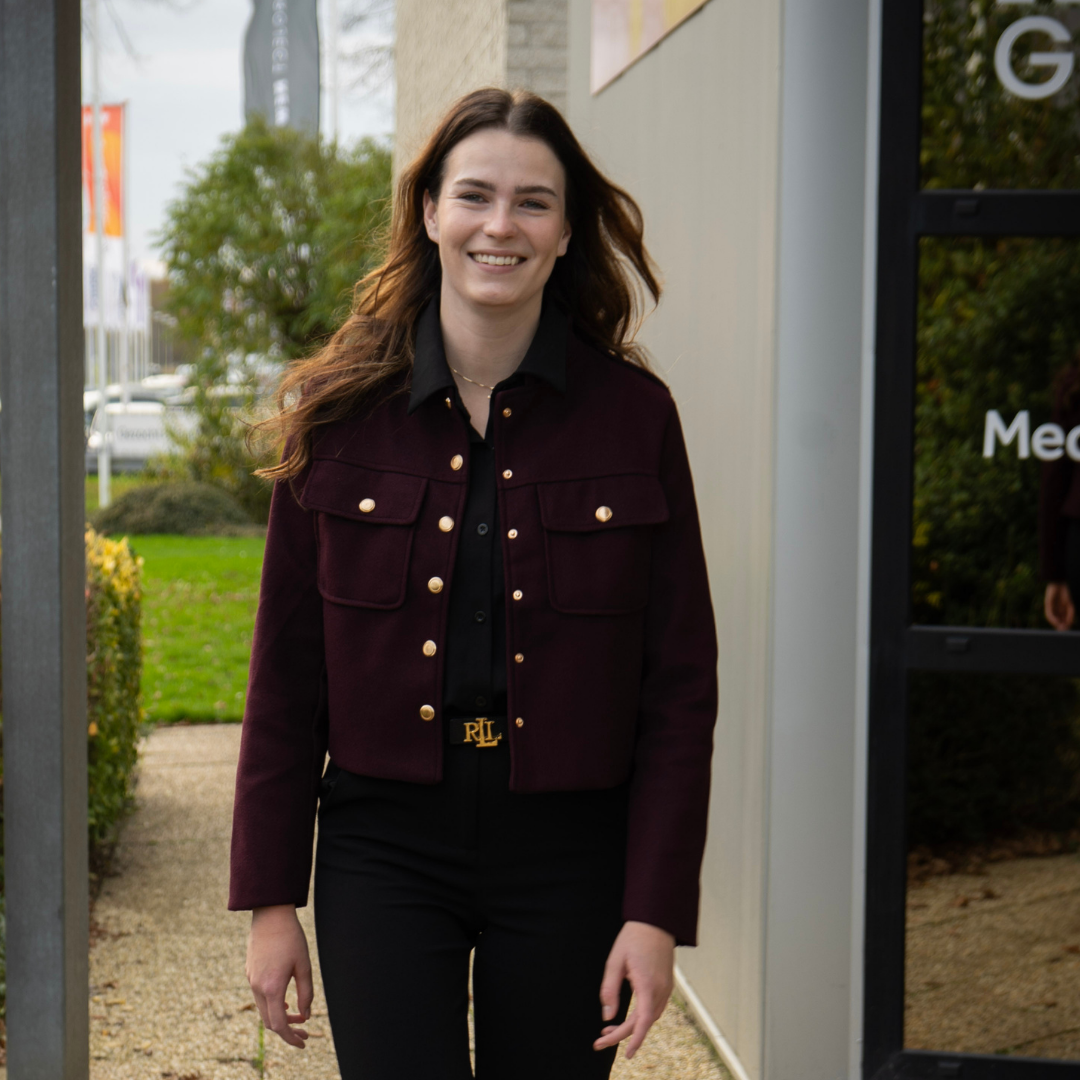 Wiltina voor het gebouw van ROK Groep met een blij gezicht loopt ze lachend richting de camera